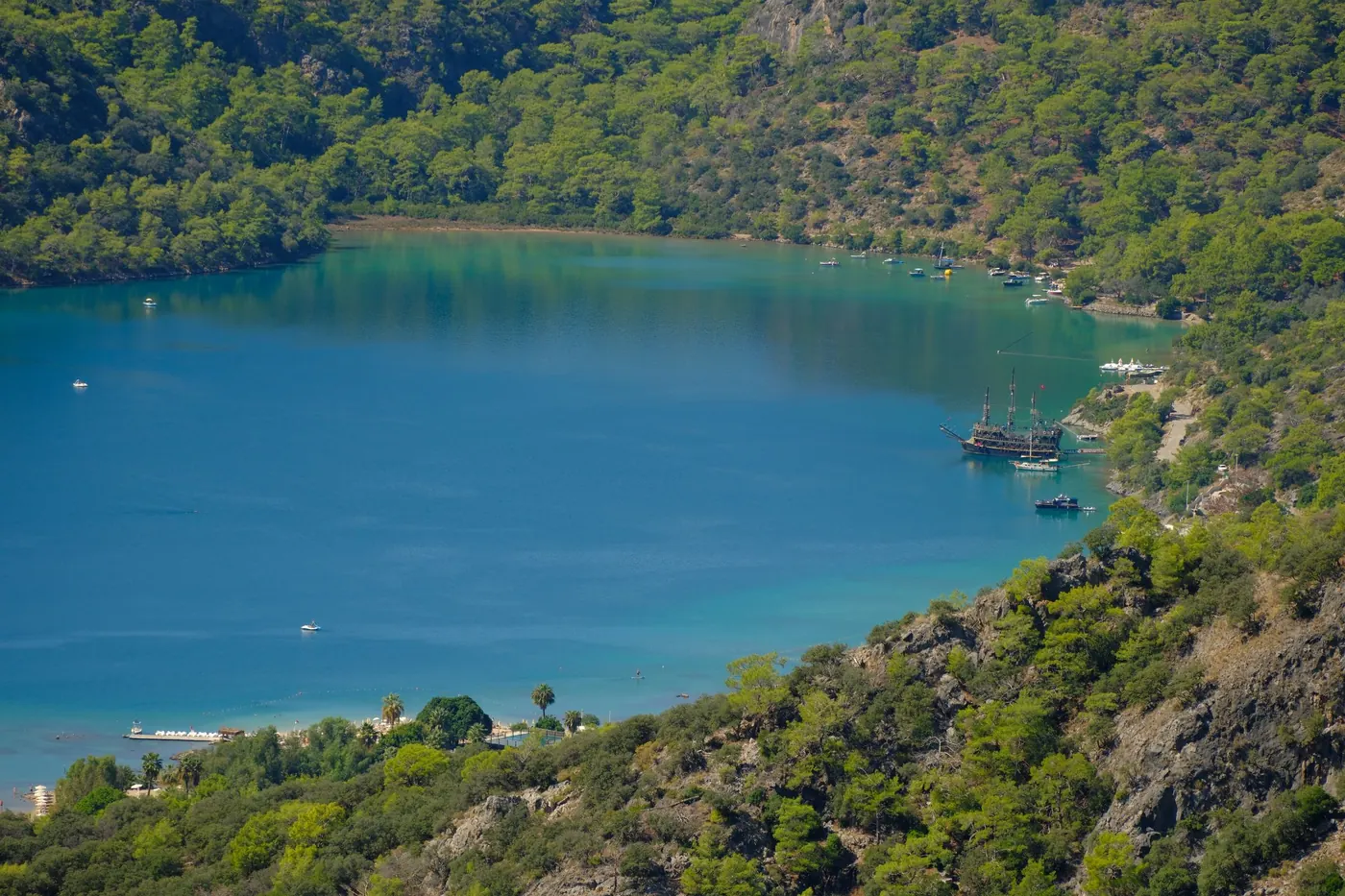 Calm blue water of the Ölüdeniz lagoon surrounded by pine-covered hills